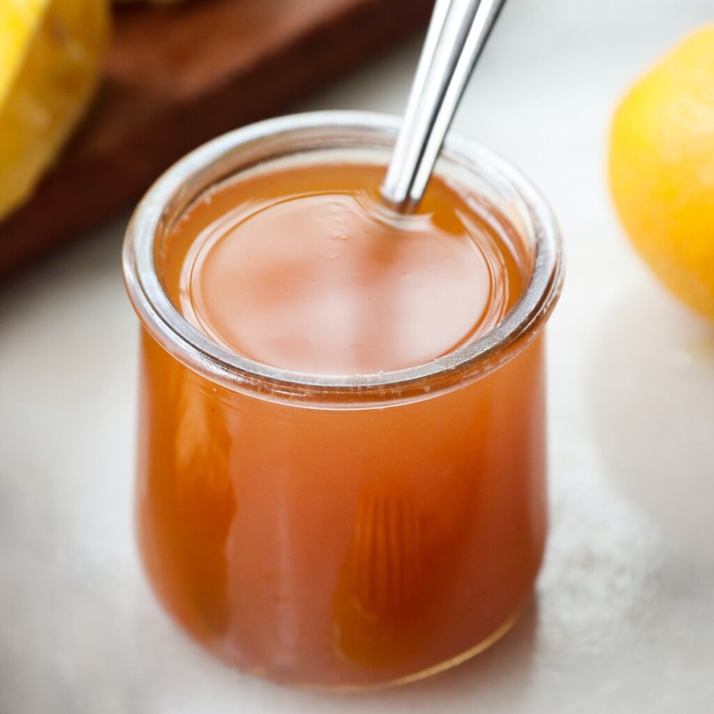 Side view of a glass jar filled with ginger brew syrup.