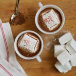 Two white cups filled with Dairy Free Hot Cocoa, topped with Peppermint Marshmallows