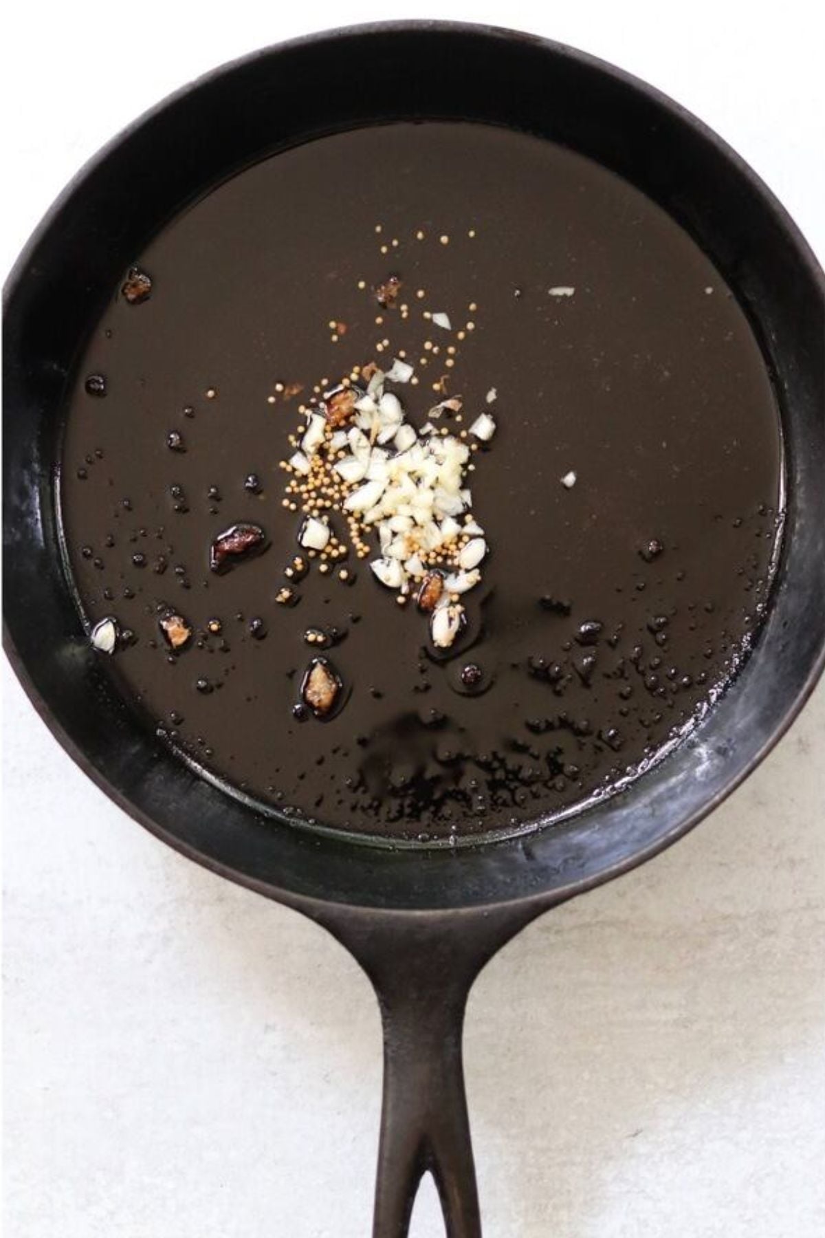 A black cast iron skillet with chopped garlic and spices.