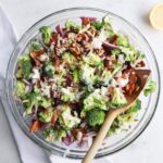 Overhead view of broccoli bacon salad tossed with creamy dressing in a glass salad bowl.
