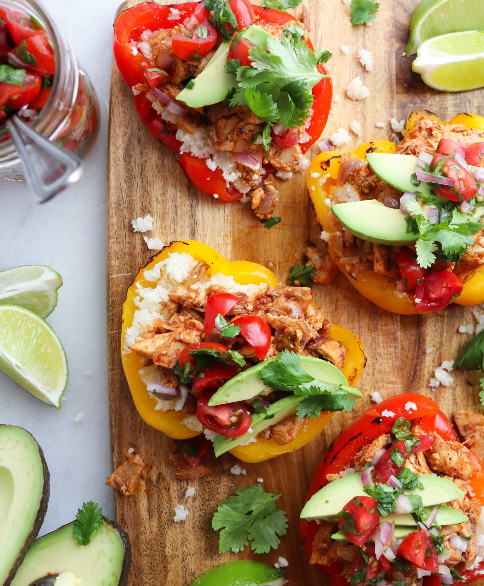 Close up of stuffed fajita bell peppers with fresh pico and avocado slices. 