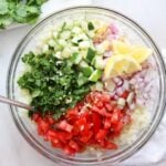 Whole30 Cauliflower tabbouleh made with cauliflower rice, cucumber, tomato, garlic, onion, and herbs, topped with lemon wedges.