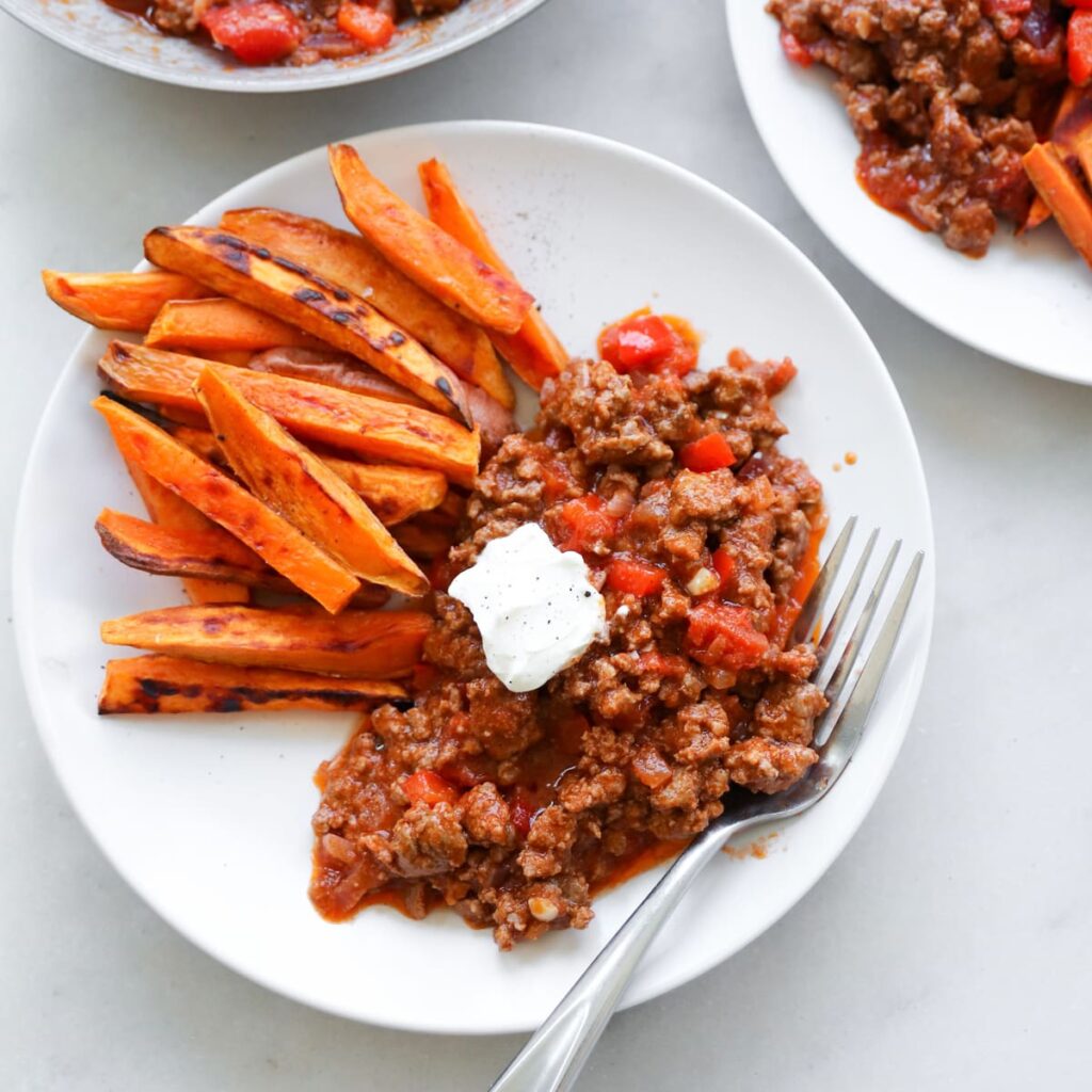Close up of a white plate with sloppy joes and sweet potato fries.