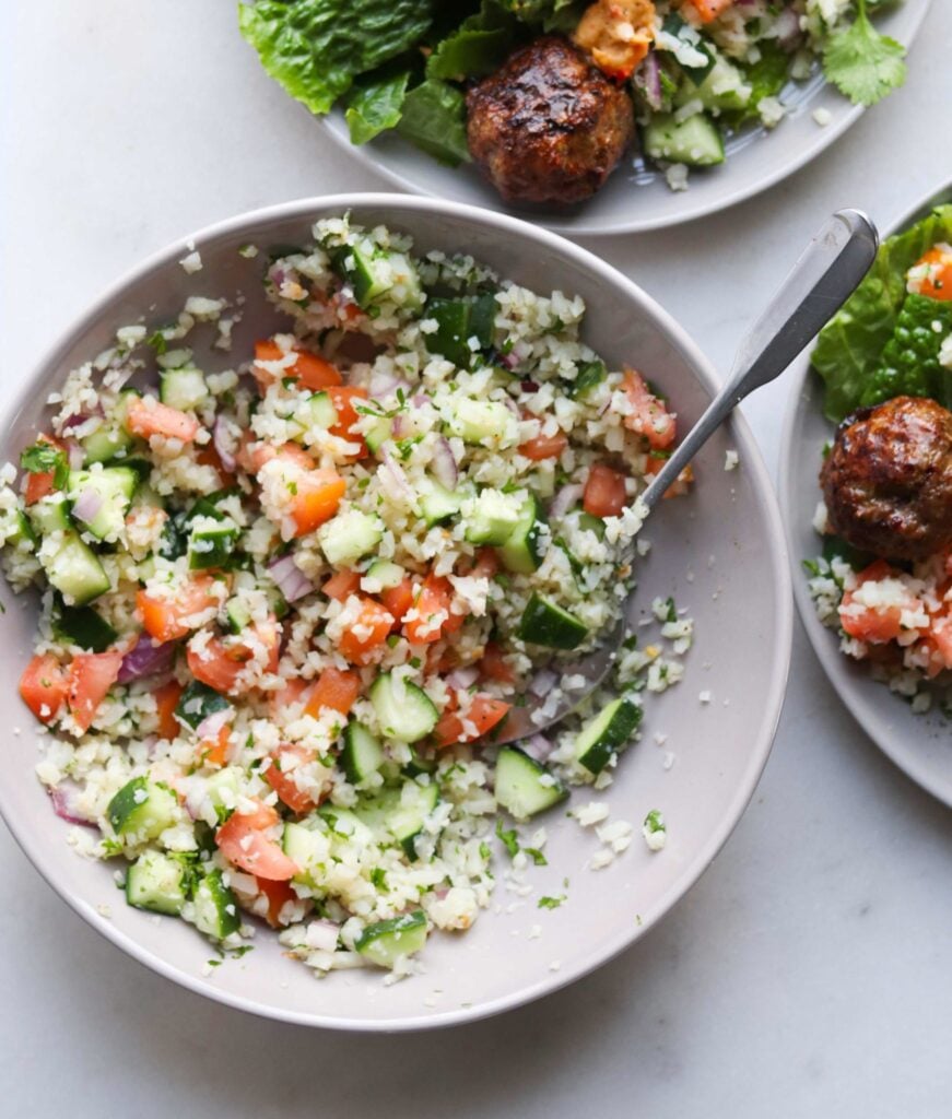 Whole30 Cauliflower Tabbouleh in a gray bowl with a silver spoon.
