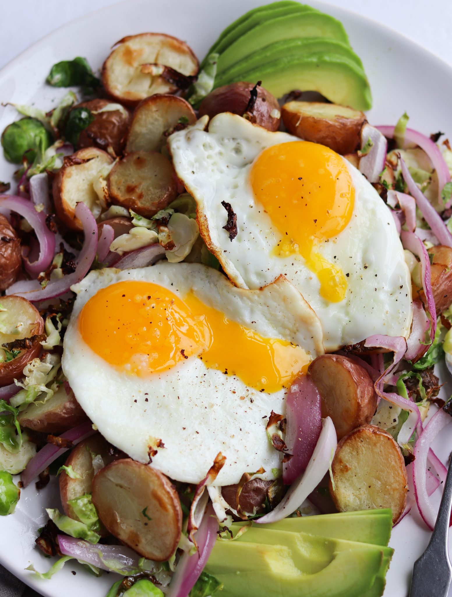 The finished dish topped with two runny fried eggs and avocado slices.