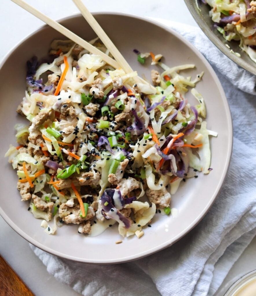 A grey bowl filled with the finished dish and a set of wooden chopsticks.