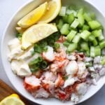 Whole30 Lobster Tail Salad, served in a white bowl with diced celery, mayo, shallots, and garnished with lemon slices.