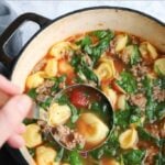 Large pot of sausage tortellini soup with title in a graphic overlay on the photo.