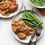 Cook pork chop on a gray plate, serve with green beans.