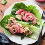 Two spicy tuna lettuce wraps on a white plate.