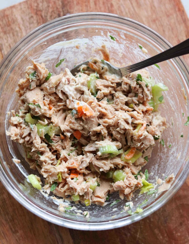 A glass bowl filled with tuna salad that's been mixed up.