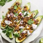 Mexican zucchini boats filled with keto ground beef, presented on a white plate.
