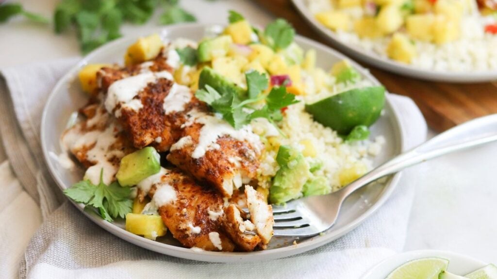 Side view of the plated blackened flounder with pineapple salsa and a drizzle of chili lime sauce.