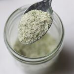 Close up of a spoon scooping some of the ranch seasoning out of a mason jar.