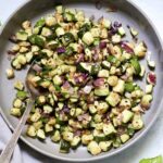 Serving spoon in a grey bowl filled with air fried zucchini and onions.