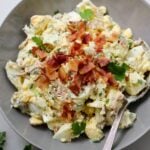 Close up of the finished egg salad in a gray bowl sprinkled with crispy bacon.