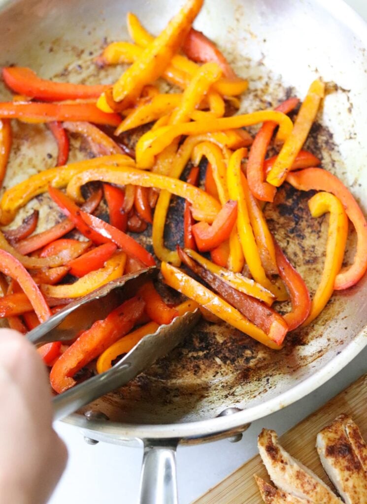 Sauteing strips of yellow and red bell peppers for fajita salad.