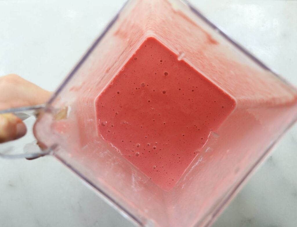 Creamy pink liquid in a blender jar.