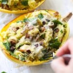 Close up of a hand holding a fork, taking a bite of the finished chicken, bacon and ranch stuffed spaghetti squash.