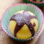 Close up of one bulletproof coffee bomb topped with pink sea salt in a paper muffin tin cup.