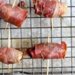 Close up of the cooked prosciutto wrapped dates on the baking sheet.