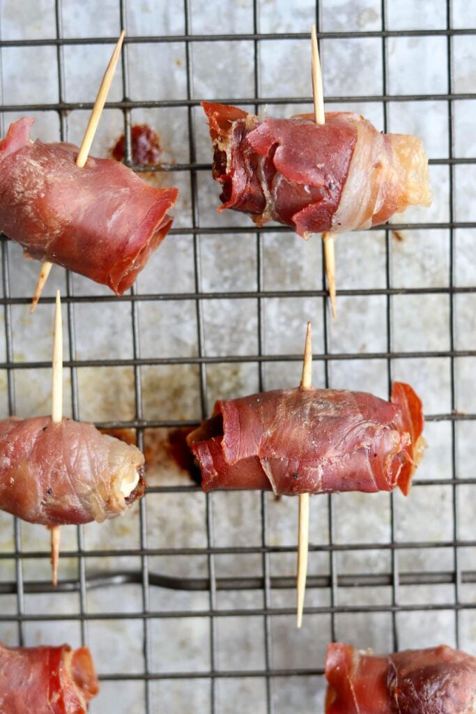 Close up of the cooked prosciutto wrapped dates on the baking sheet.