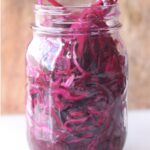Side view of a mason jar filled with pickled red cabbage.