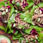 Close up of four cooked and assembled lettuce wraps on a wooden board.