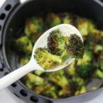 A serving spoon close up with roasted broccoli.