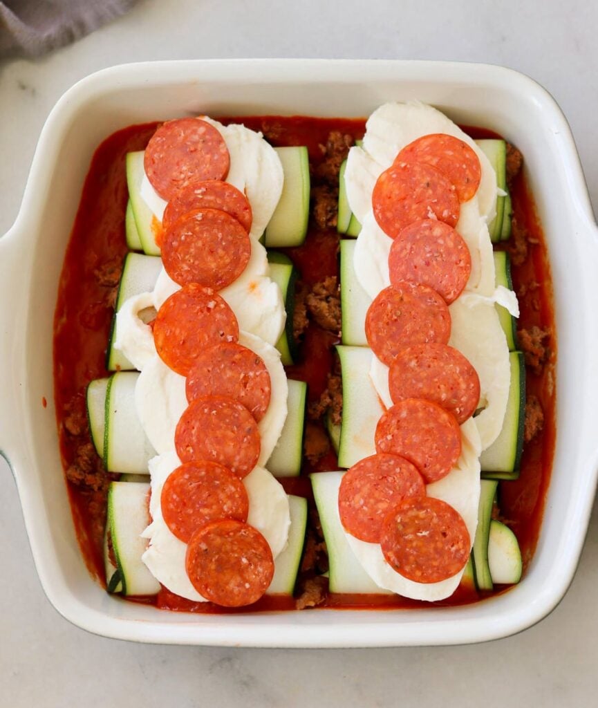Unbaked Italian zucchini roll ups in a casserole dish.