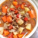 Close up of a bowl of poor man's stew with a spoon.