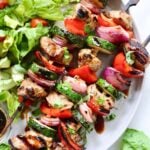Plated pork kebabs with bell peppers, red onion, and zucchini.