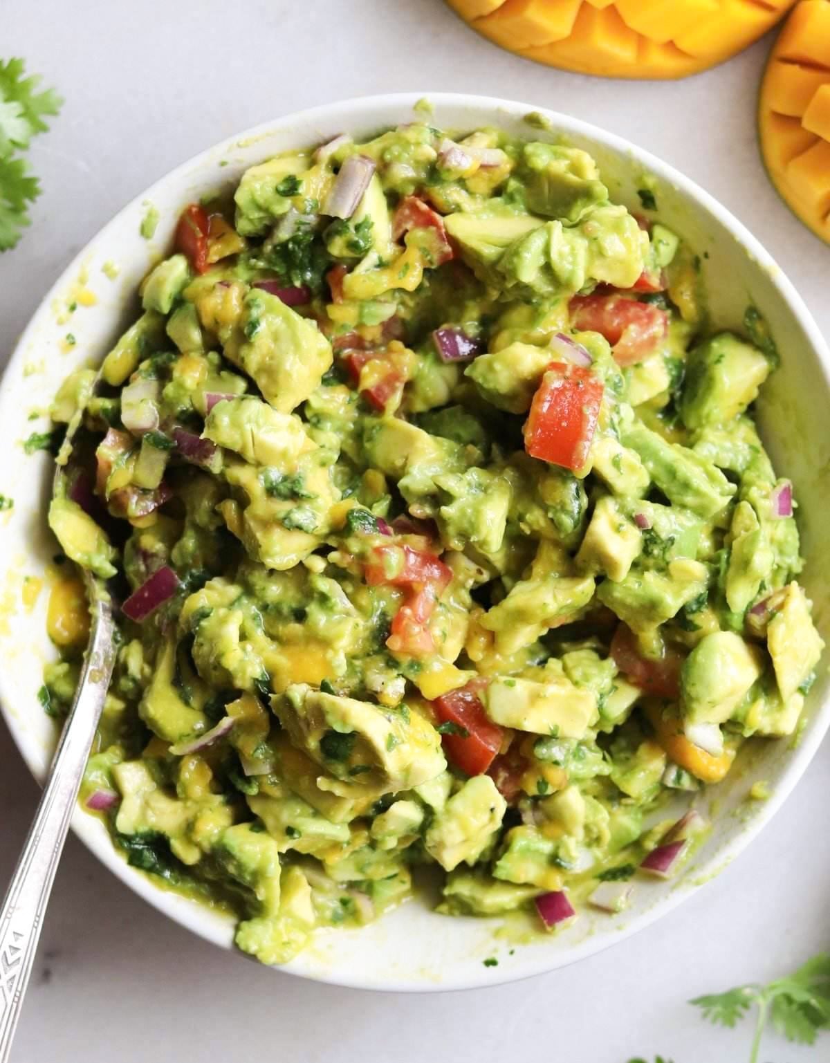 A white bowl filled with finished mango guacamole.