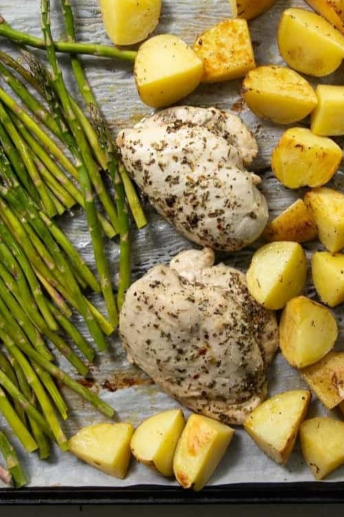 Sheet pan chicken and potatoes with asparagus spears, all seasoned and baked to perfection.