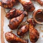 Sticky bbq chicken drumsticks on parchment paper.