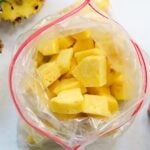 Top down off frozen pineapple pieces inside a zip top bag.