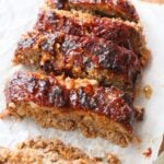 Sliced air fryer meatloaf on a parchment lined cutting board.