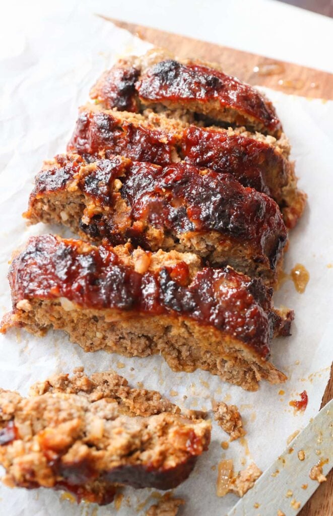 Sliced air fryer meatloaf on a parchment lined cutting board.