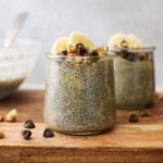 Close up side view of banana chia pudding in a jar topped with chocolate chips, walnuts, and banana slices.