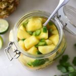 Top down looking into a large masin jar filled with diced pickled pineapple and jalapenos.