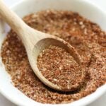 Side view of a small dish of bbq rub with a wooden spoon.
