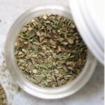 Top down of a small glass jar filled with greek seasoning.