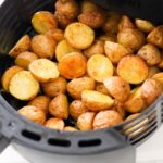 Close up of cooked baby potatoes in an air fryer basket.