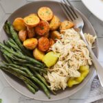A gray plate filled with Mississippi shredded chicken, potatoes, and green beans.