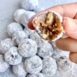 A hand holding one pecan pie ball with a bite taken out.