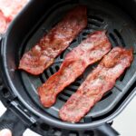 Three pieces of crispy turkey bacon inside an air fryer basket.