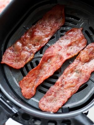Three pieces of crispy turkey bacon inside an air fryer basket.