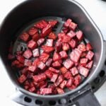 Diced beets inside an air fryer basket.