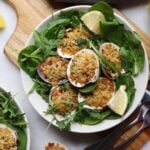 Close up of baked clams oreganata in a bowl with spinach and lemon slices.