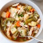 A gray bowl filled with crockpot chicken stew, potatoes, carrots, and green beans.